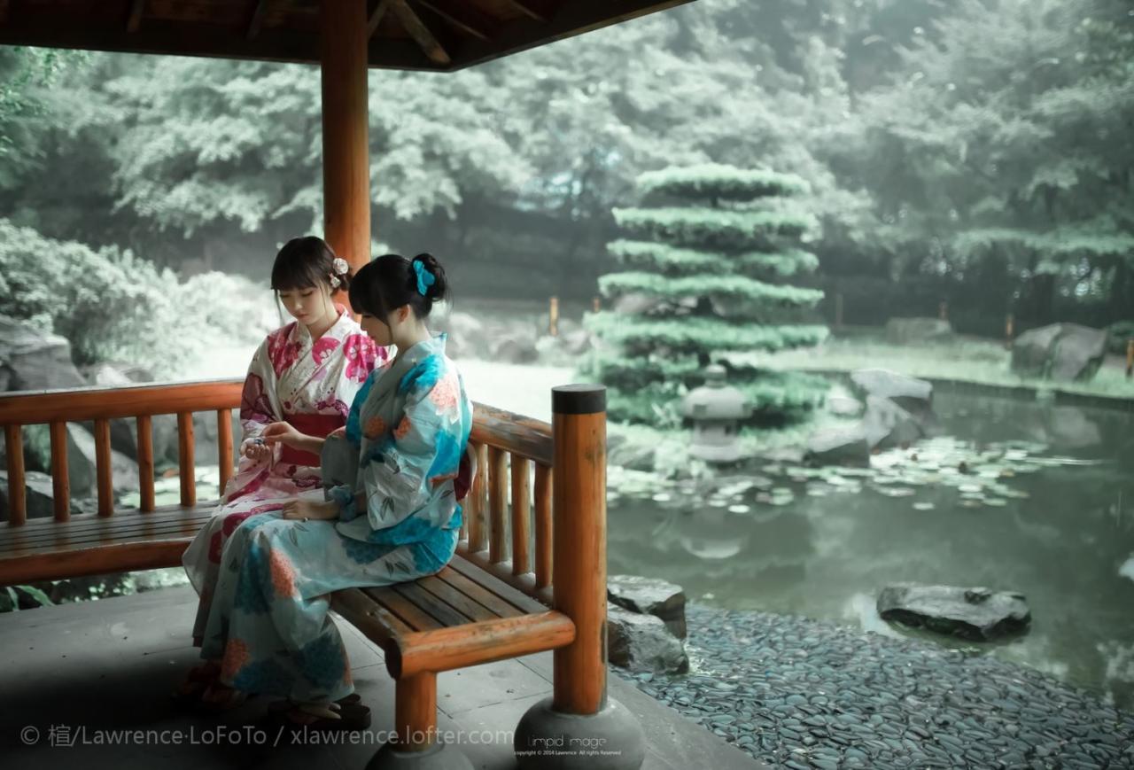 粉色浴衣和蓝色浴衣少女坐在水潭旁的亭子里