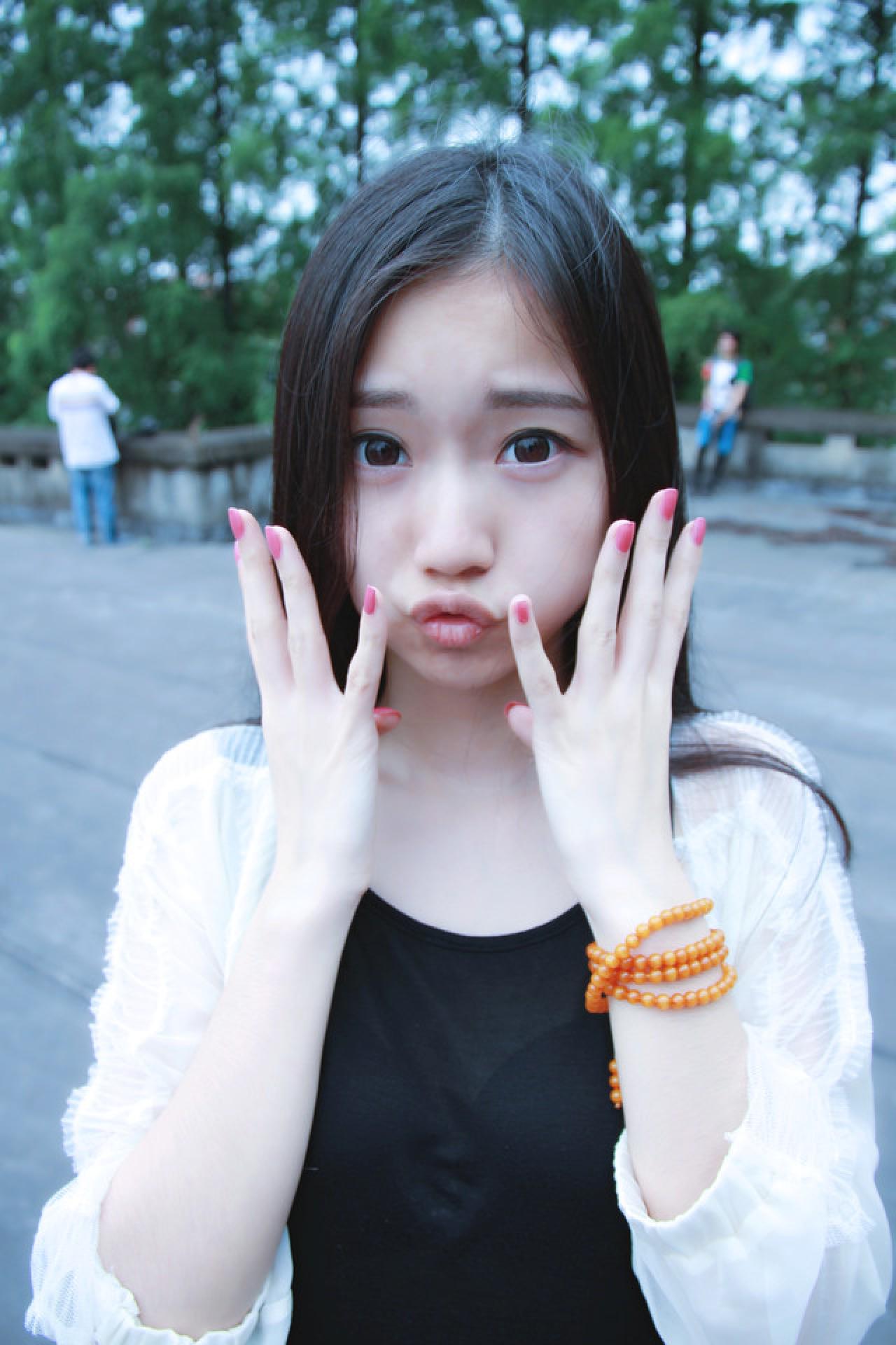 黑长直萌妹子吃惊的神情：双手放在脸颊两侧，嘟嘴卖萌