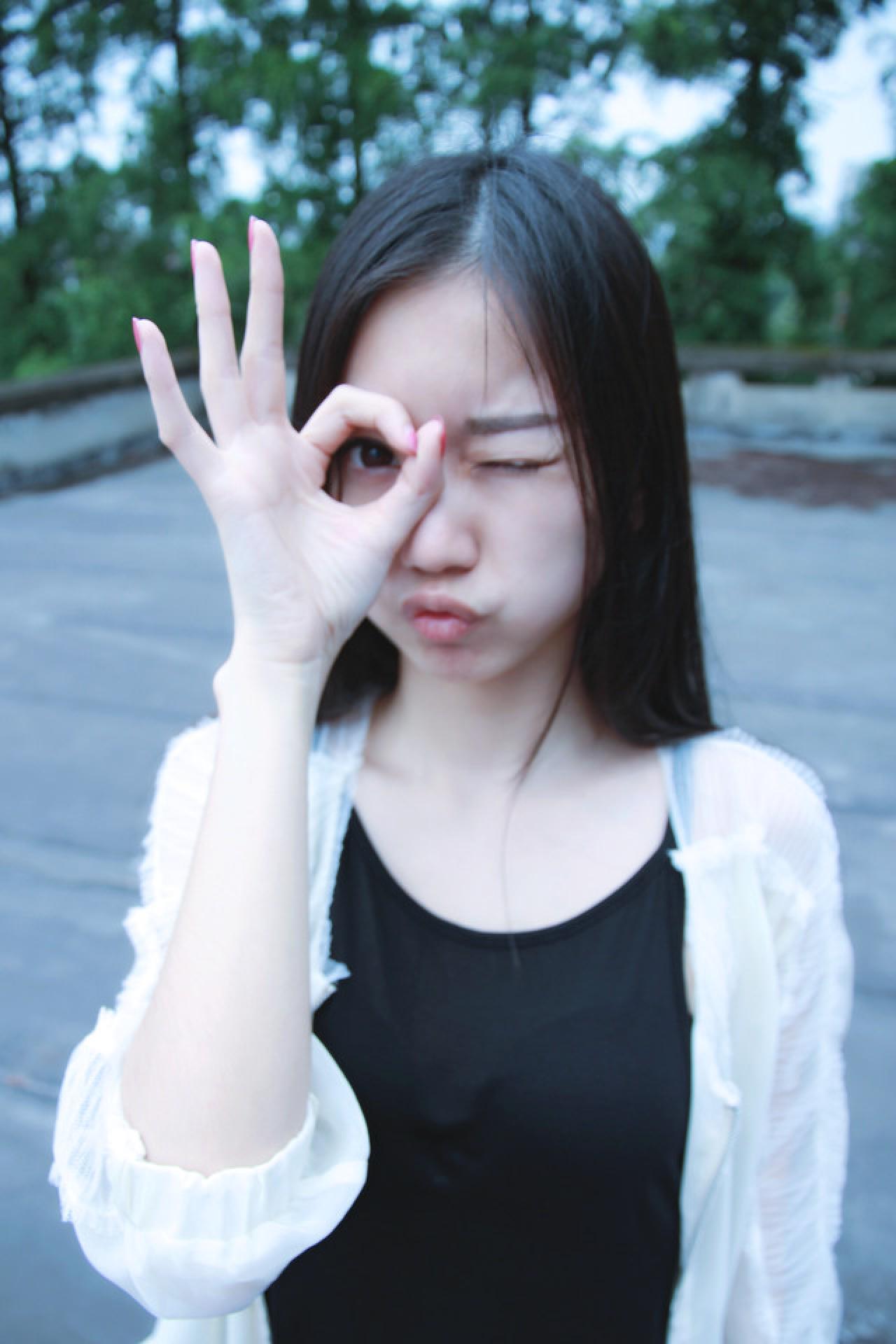 黑长直萌妹子透过OK手势眨眼睛卖萌