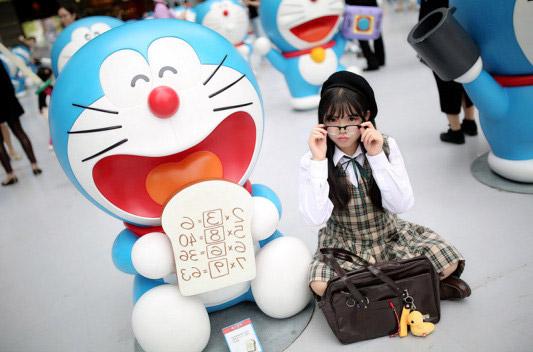 彩虹姐姐靠在举着乘法口诀的哆啦A梦旁，扶了扶眼镜镜框