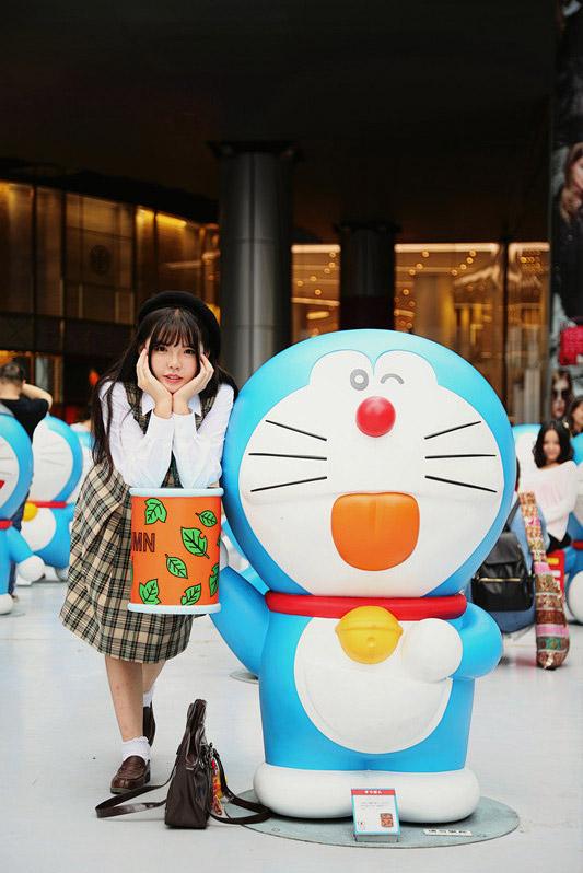 彩虹姐姐双手捧着脸扒在吐舌哆啦A梦的圆筒上