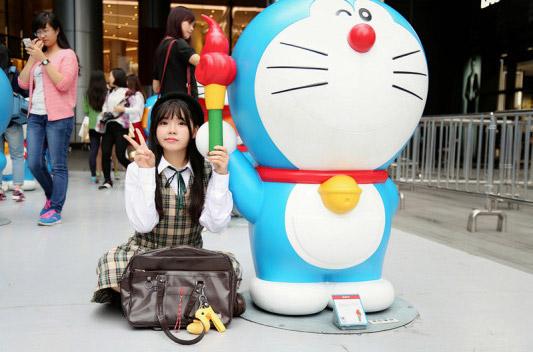 彩虹姐姐作剪刀手势和哆啦A梦一起举着火炬