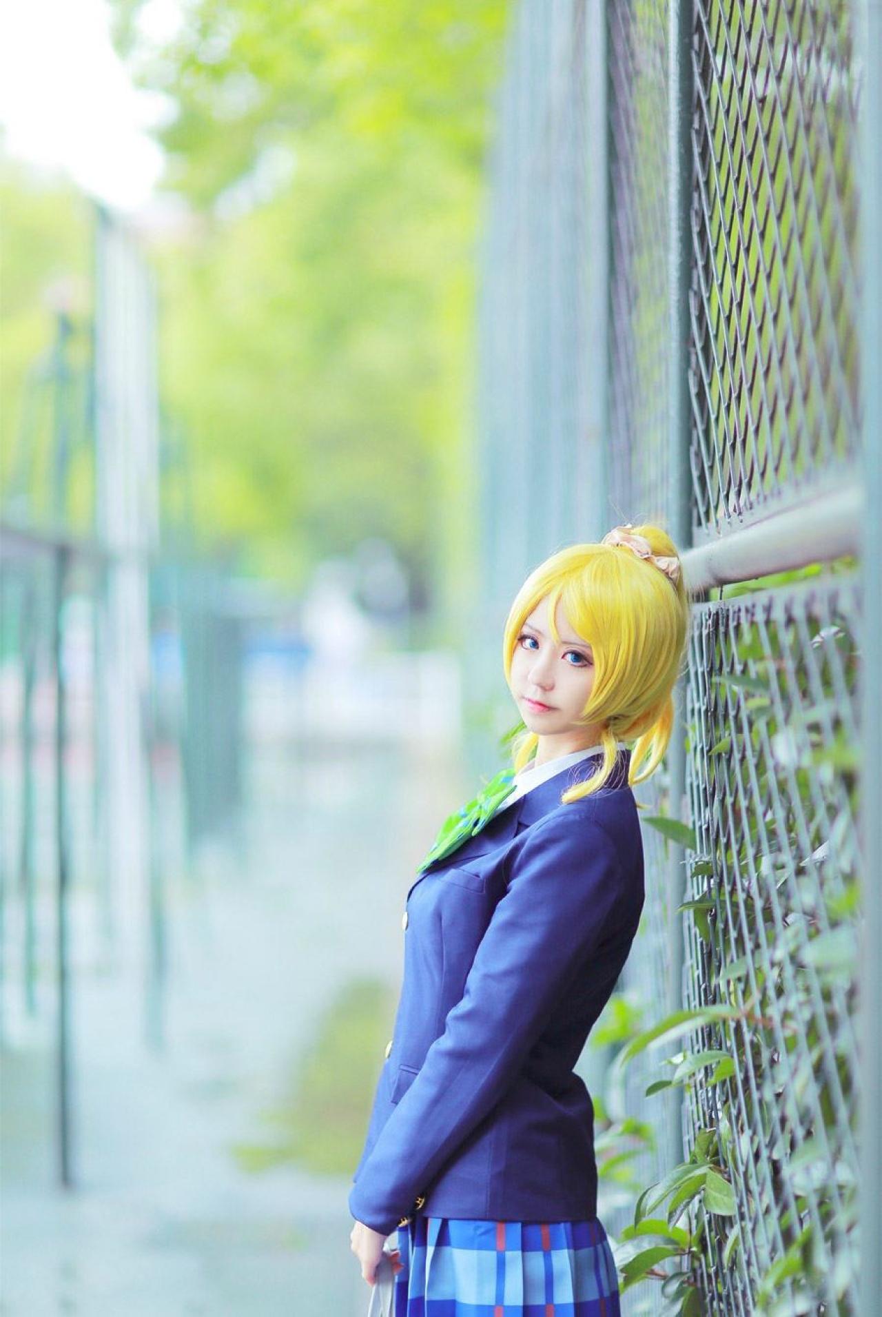 赤澤Aki扮演绚濑绘里提着包在操场的铁丝网前侧面照