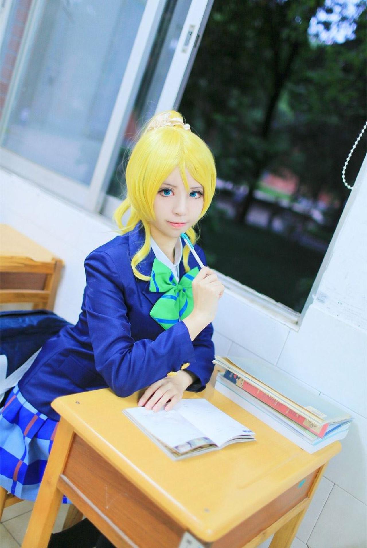 赤澤Aki扮演绚濑绘左手放在课桌上，右手拿着笔抵着下巴