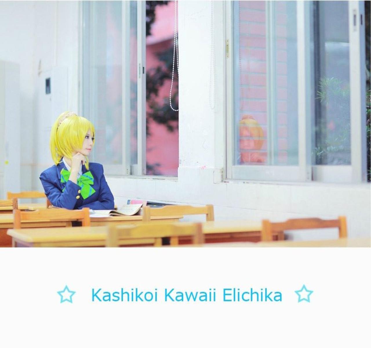 赤澤Aki扮演绚濑绘右手轻抚下巴，斜看着窗外，底部的文字为：☆Kashikoi Kawaii Elichika☆（かしこいかわいいエリーチカ罗马音，中文翻译为聪明可爱的绘里）