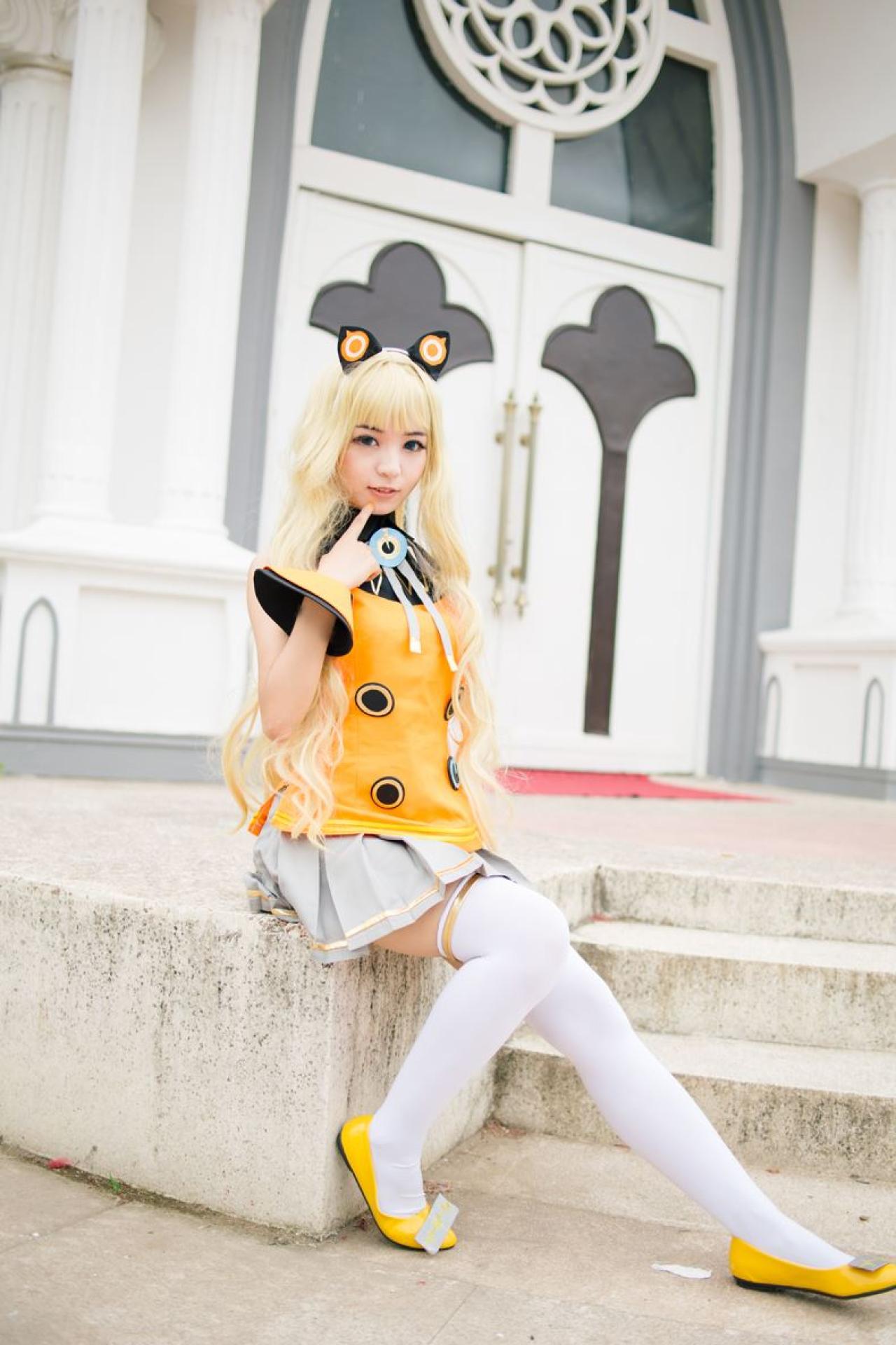 寻寻王扮演SeeU坐在台阶旁的石台上，右手手指戳下巴