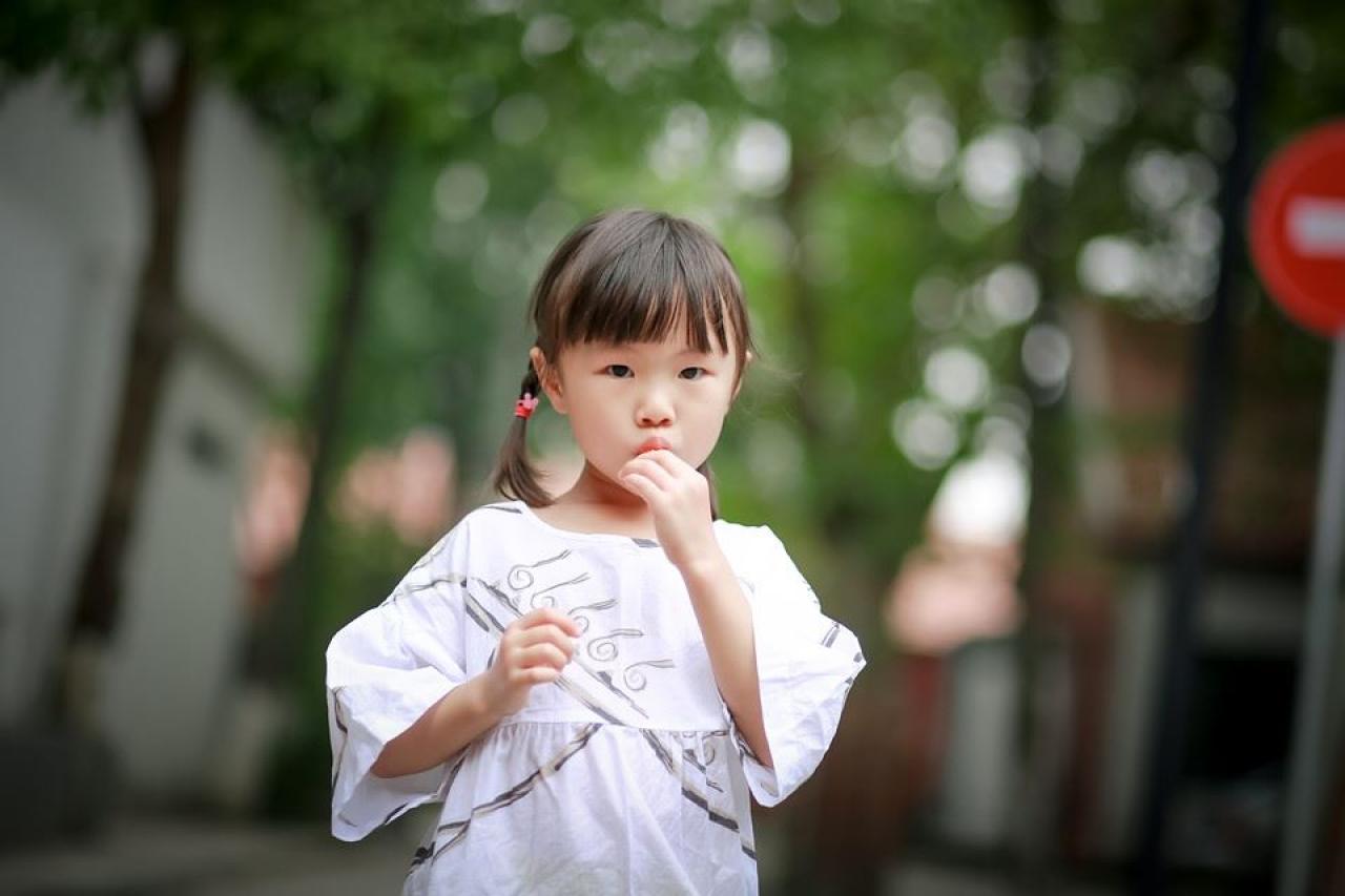 小女孩将棒棒糖放入口中