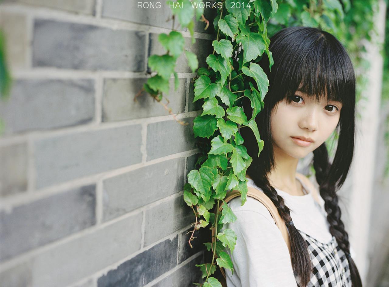 双马尾辫萌妹子靠在有爬山虎的砖墙上