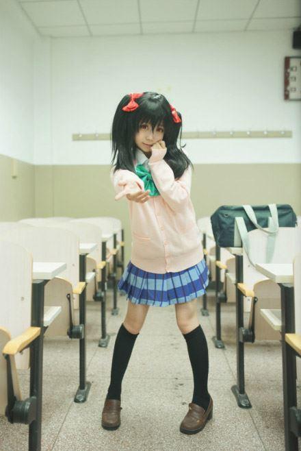 阿琴扮演矢泽妮可站在过道，左手贴着脸颊，右手伸出，作害羞邀请状