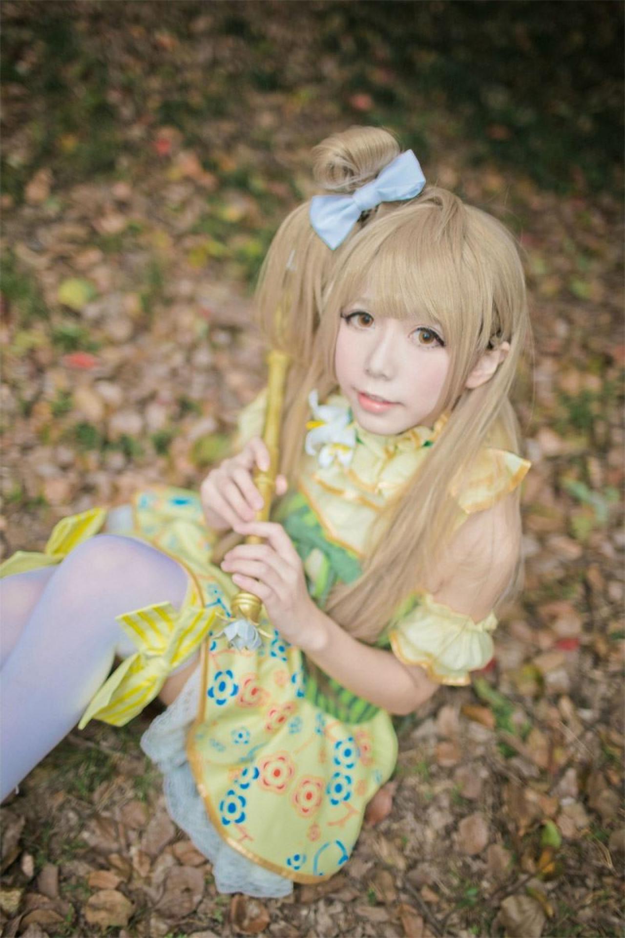 胡纸姐姐扮演南小鸟坐在落叶堆上，双手拿着风铃花手杖