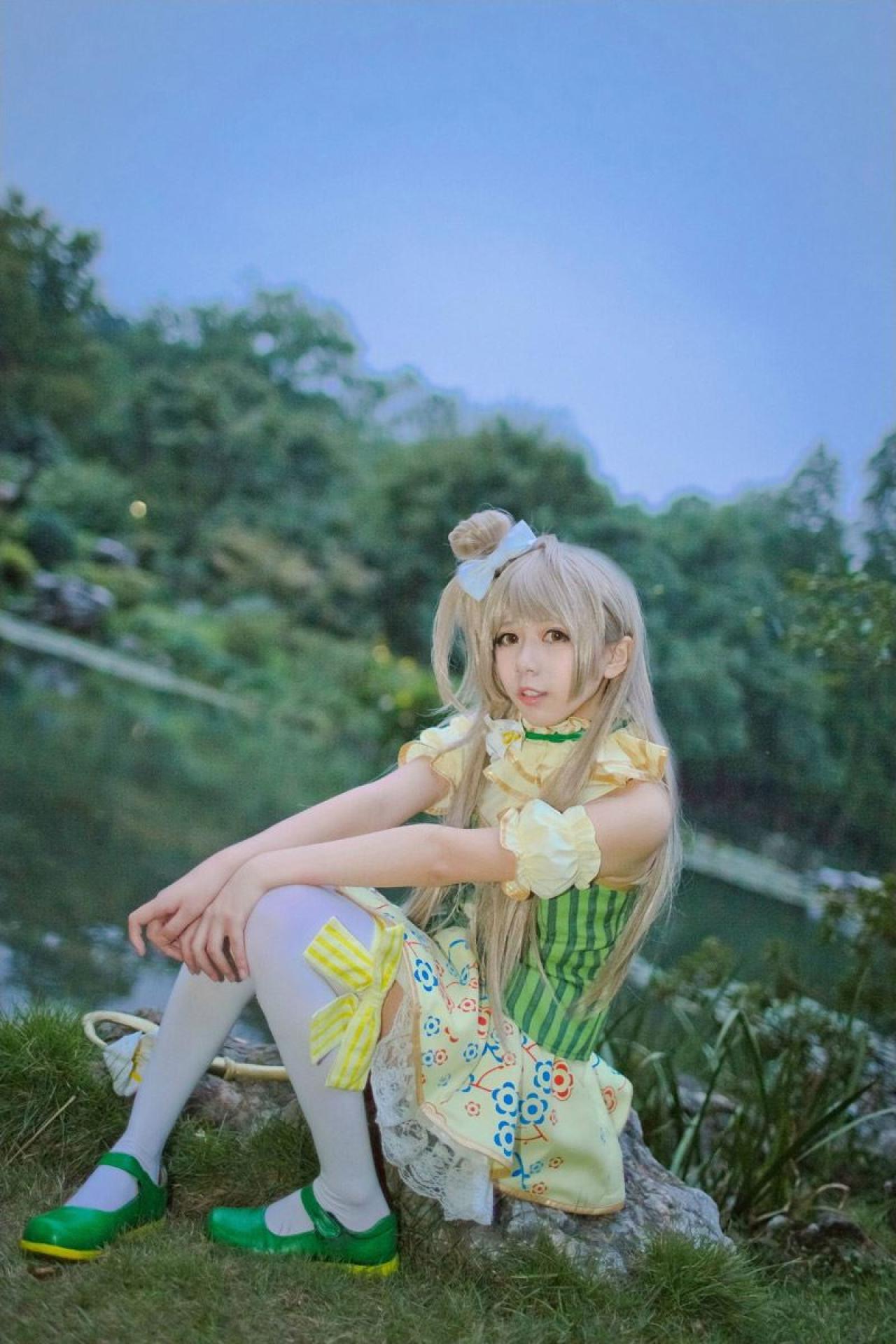 胡纸姐姐扮演南小鸟坐在湖边，手杖放到一旁，双手放在膝盖上