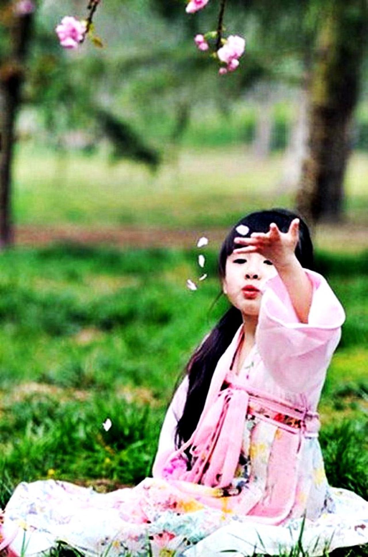 果果坐在草地上嘟嘴吹起樱花花瓣