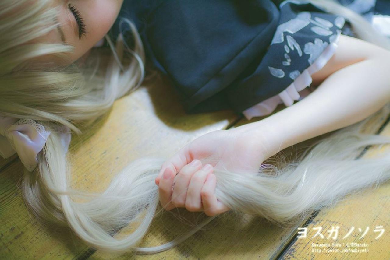 七奈扮演春日野穹躺在地上，闭着眼睛，右手轻捋马尾