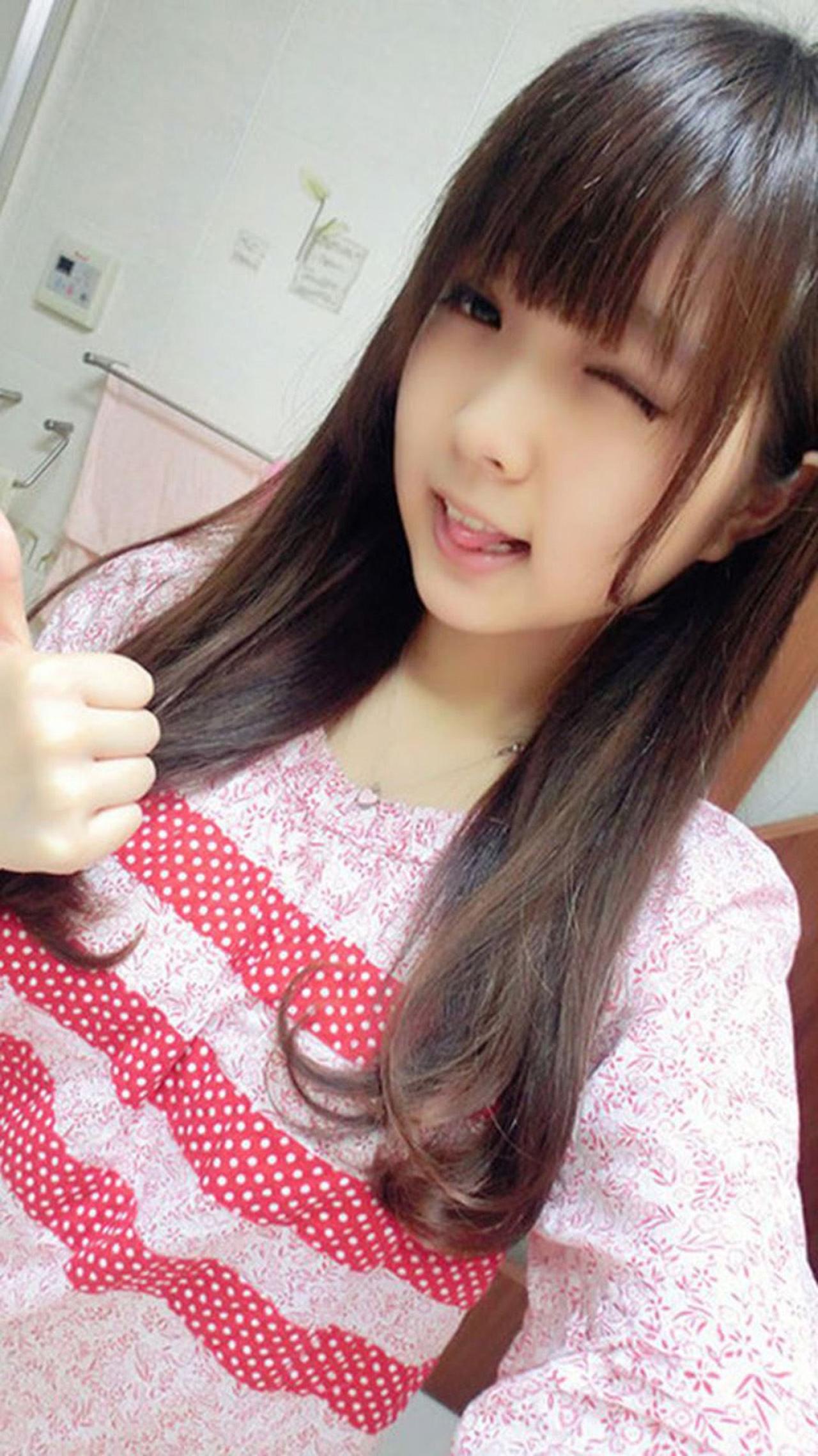 穿着粉色上衣的萌妹子嘟嘴，咬着舌头、竖起大拇指卖萌自拍手机壁纸。