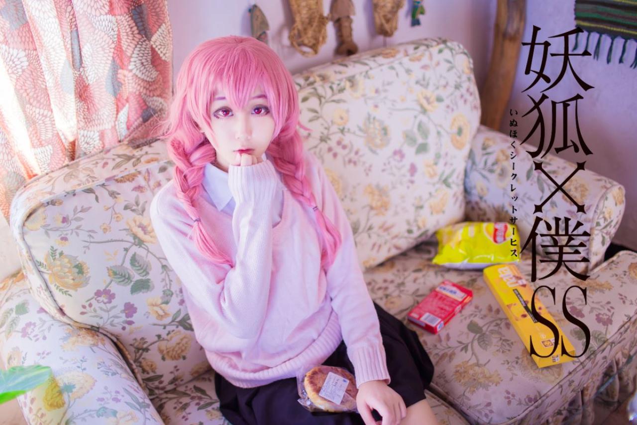 菌子扮演髅髅宫歌留多右手轻抚下巴坐在沙发上，沙发上摆着零食包装袋和盒子