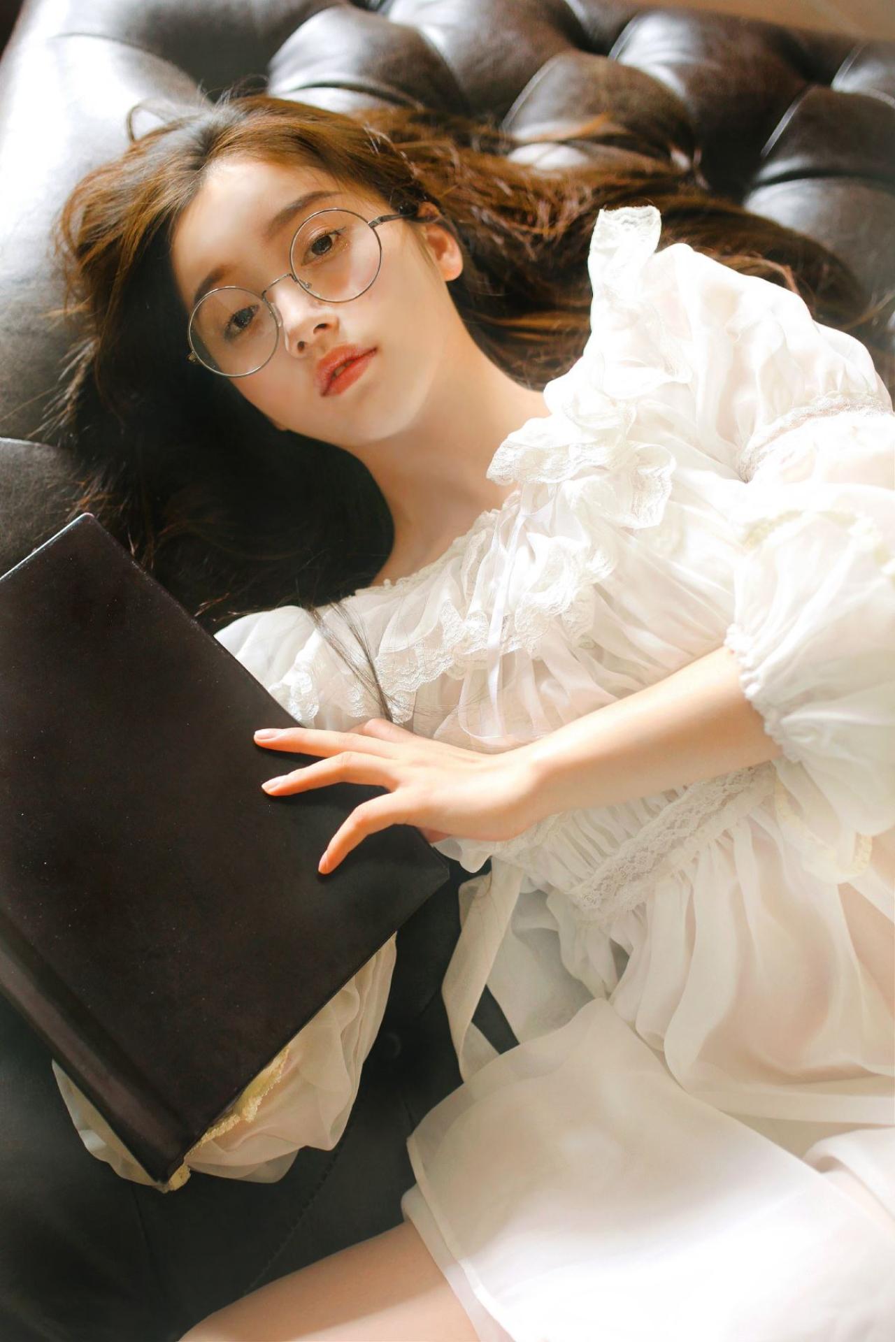 垚昕拿着黑色课本穿着白色连衣裙躺着看向镜头