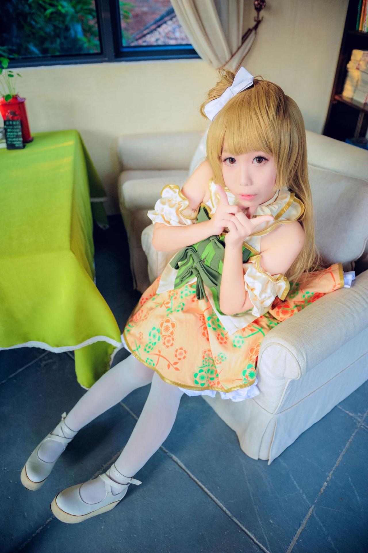 七喵扮演南小鸟坐在沙发，双手靠在一起，各伸出食指，嘟嘴卖萌