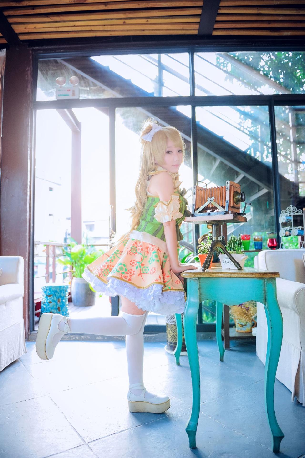 七喵扮演南小鸟双手撑在桌面，桌子上放着复古的相机