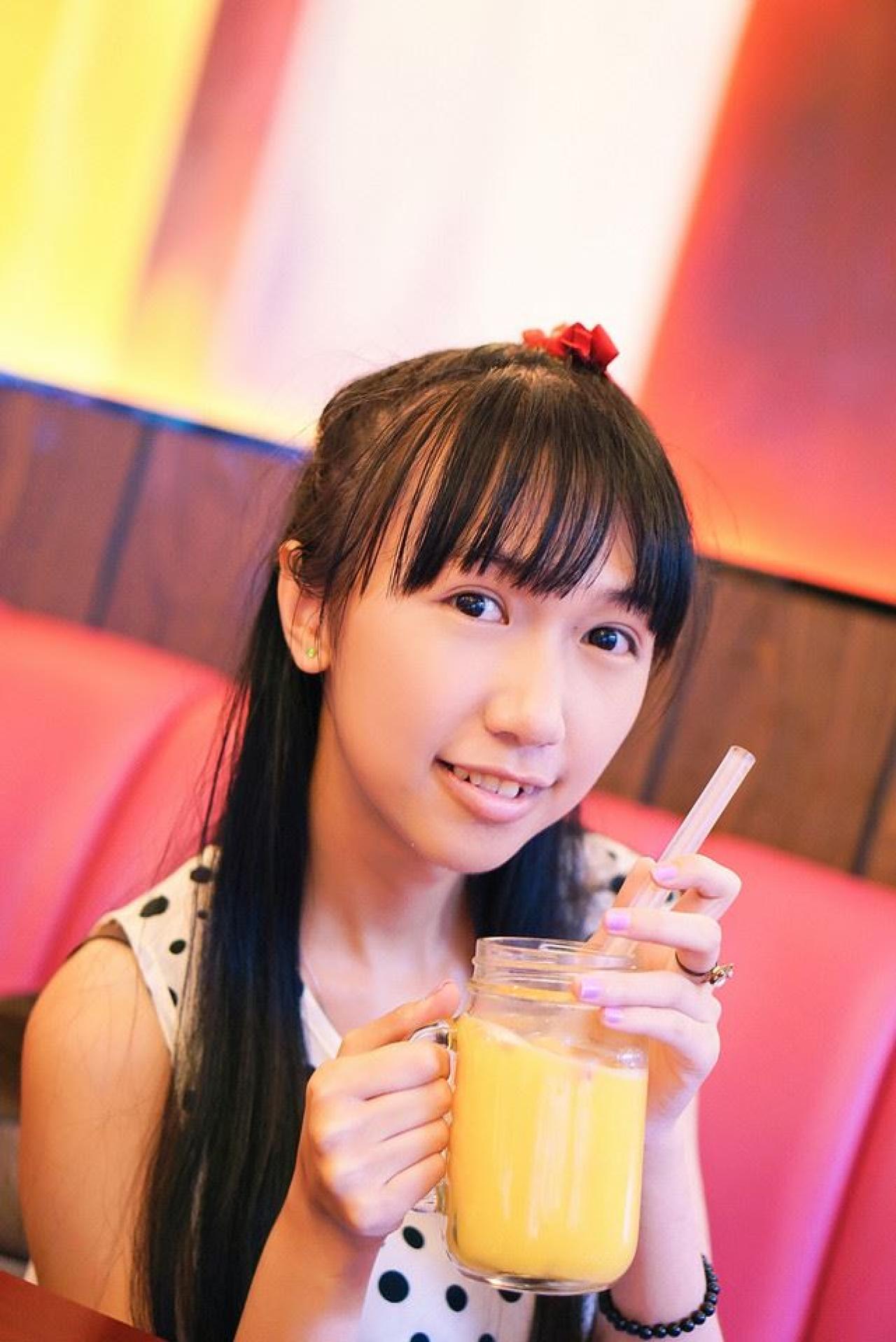 忧忧右手端着杯子，左手扶着吸管