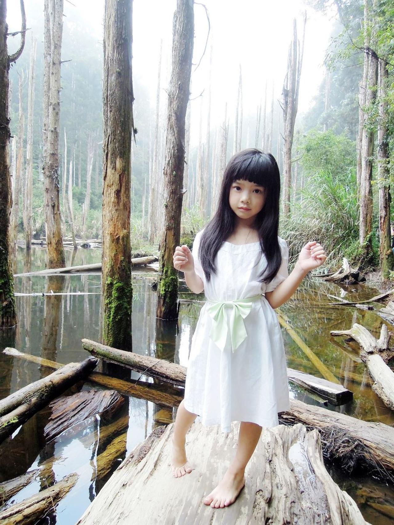 Yui站在水中的树干上，双手抬起