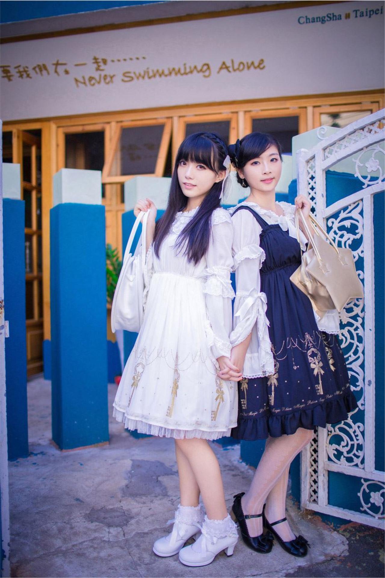 katy和江湾提着包，手腕手靠在一起的样子