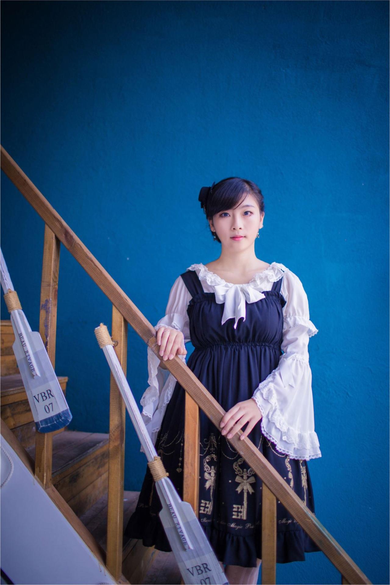 江湾站在楼梯台阶上，双手扶着楼梯扶手