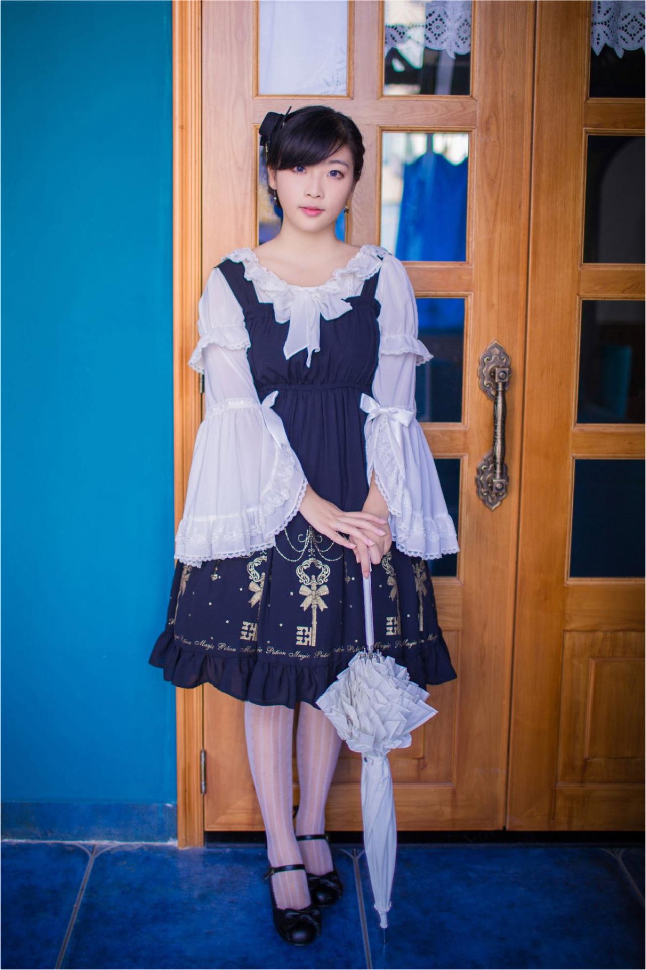 江湾双手放在腰间，持伞站在门前