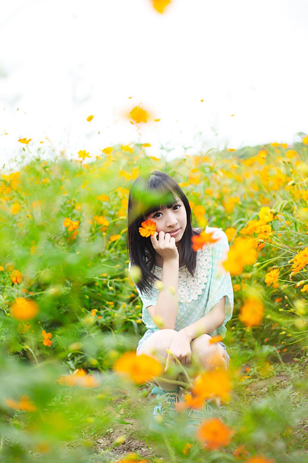 彤彤蹲在花丛中，右手握着一朵花贴着脸庞