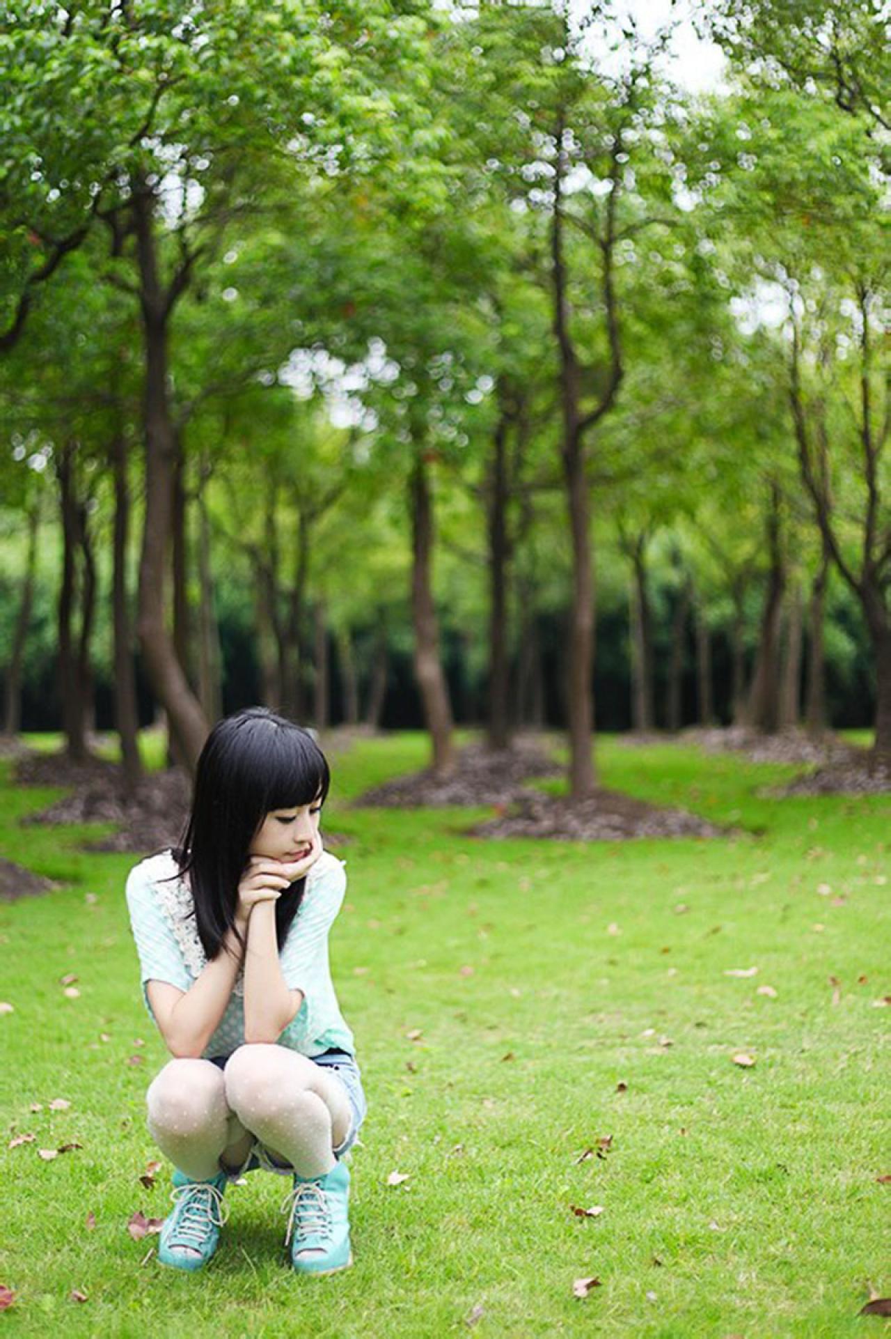 彤彤蹲在草地上，双手撑着下巴，侧头看着草地