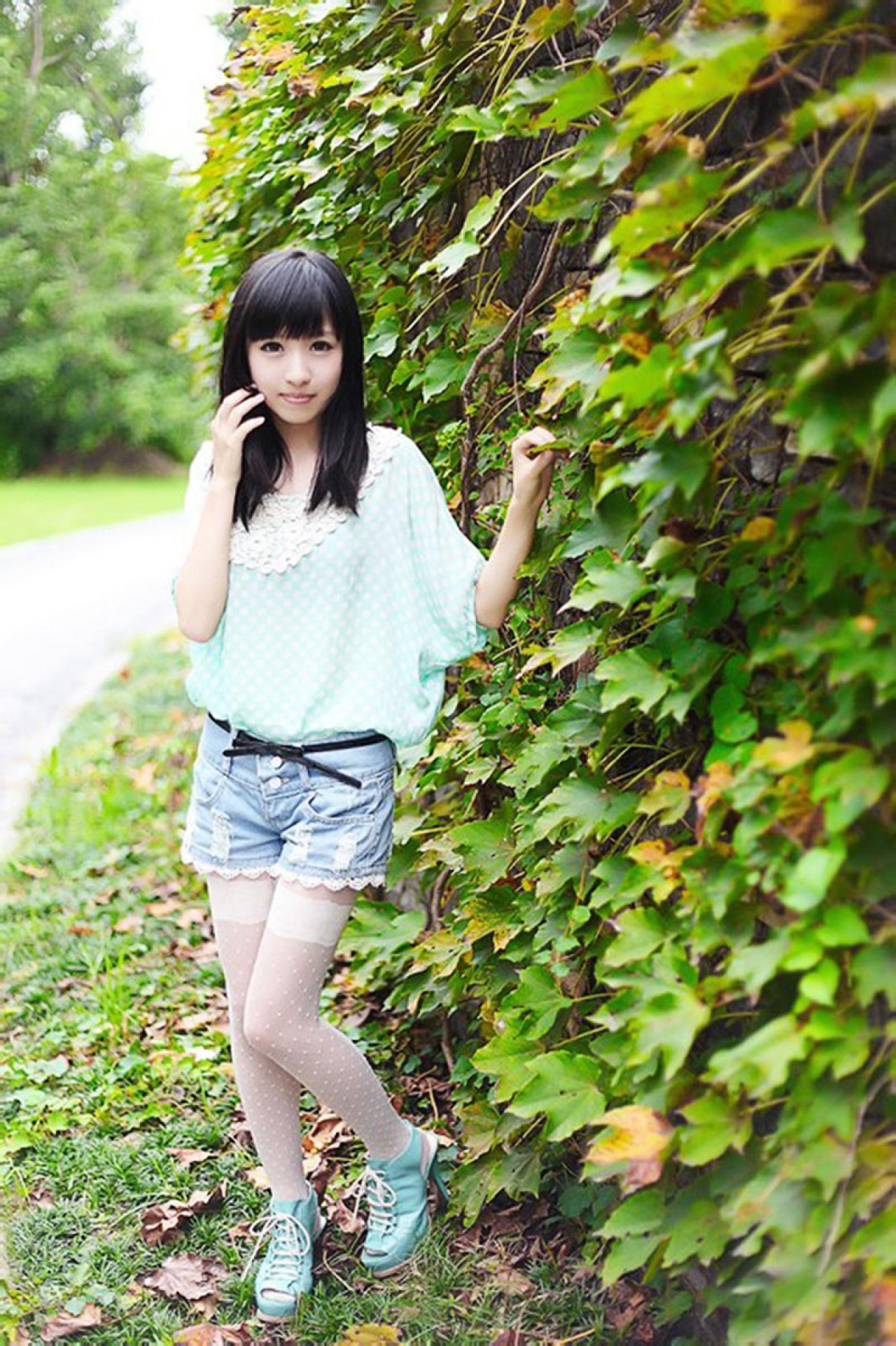 彤彤左手扶着爬山虎的叶子，右手手指贴着脸庞