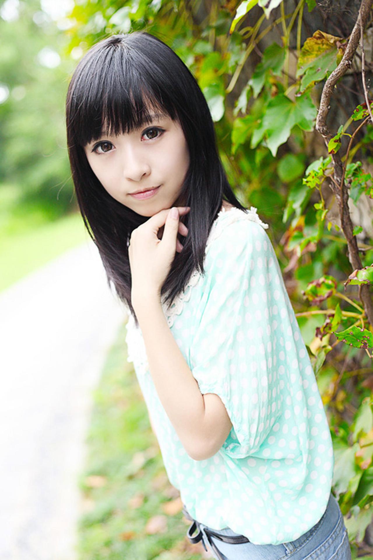 彤彤左手扶着下巴站在一墙爬山虎前的侧面