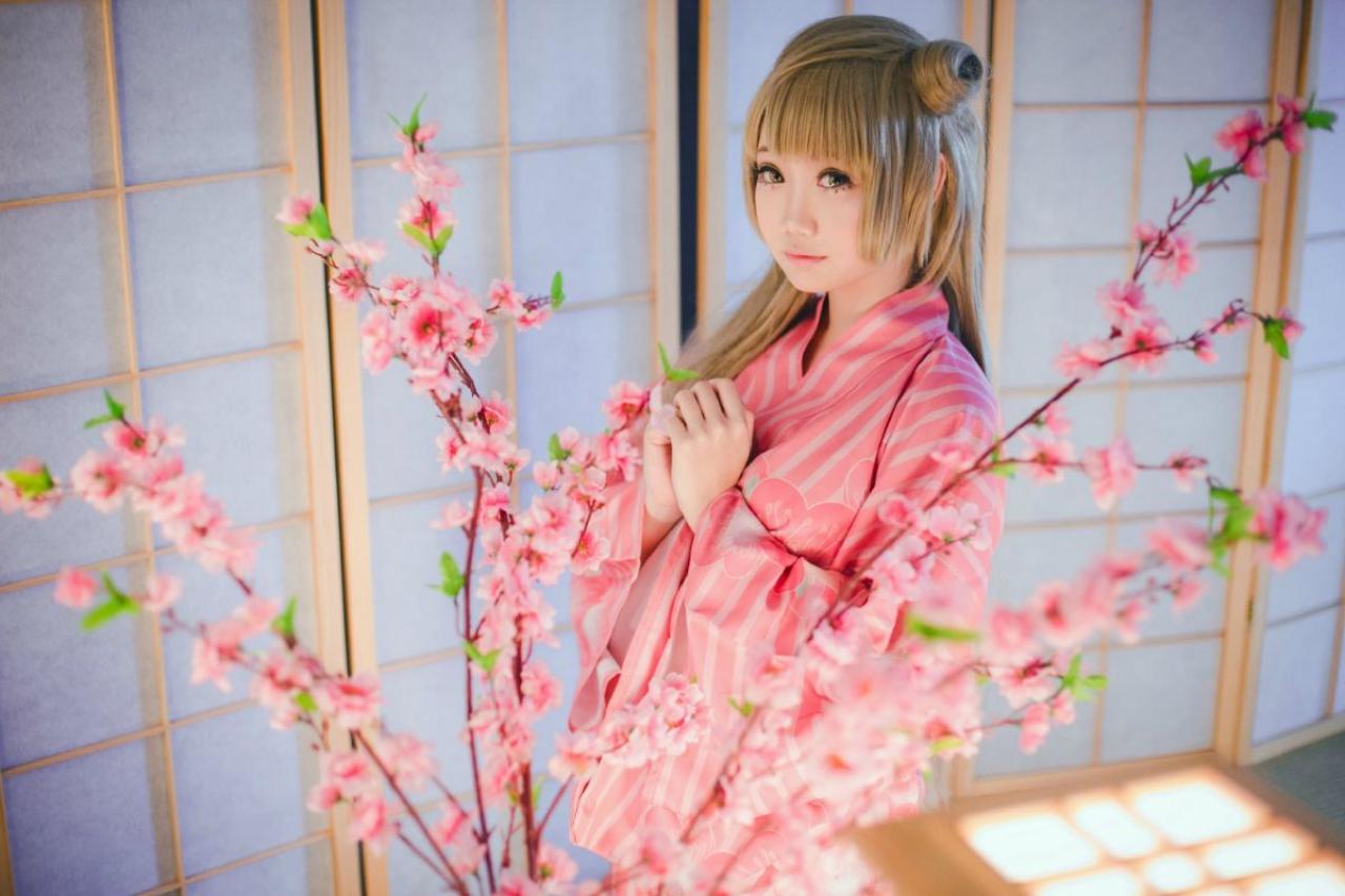 焖焖子扮演南小鸟双手靠在一起放在胸前，站在樱花后