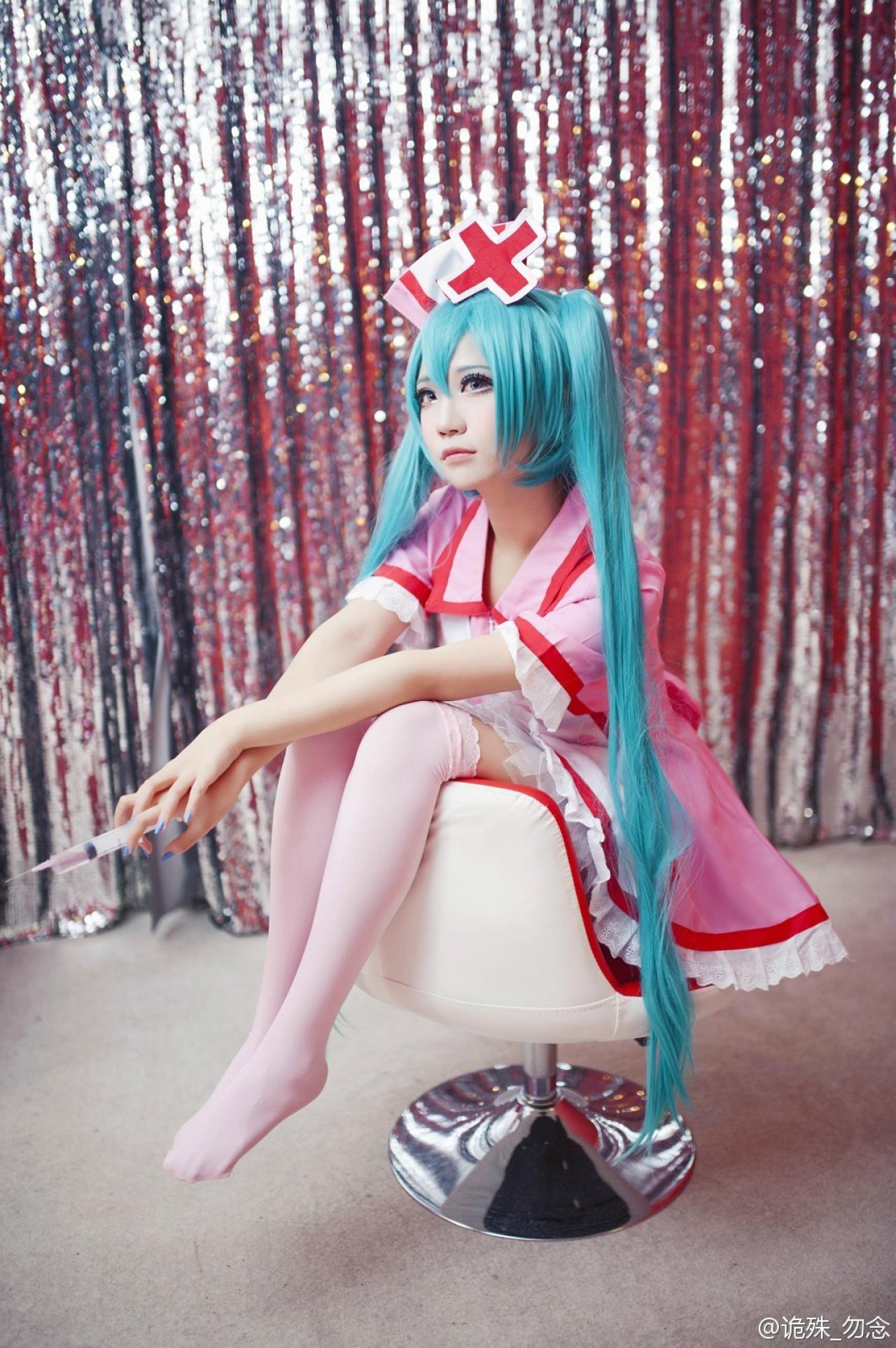 诡殊扮演初音未来坐在椅背上，右手拿着针管