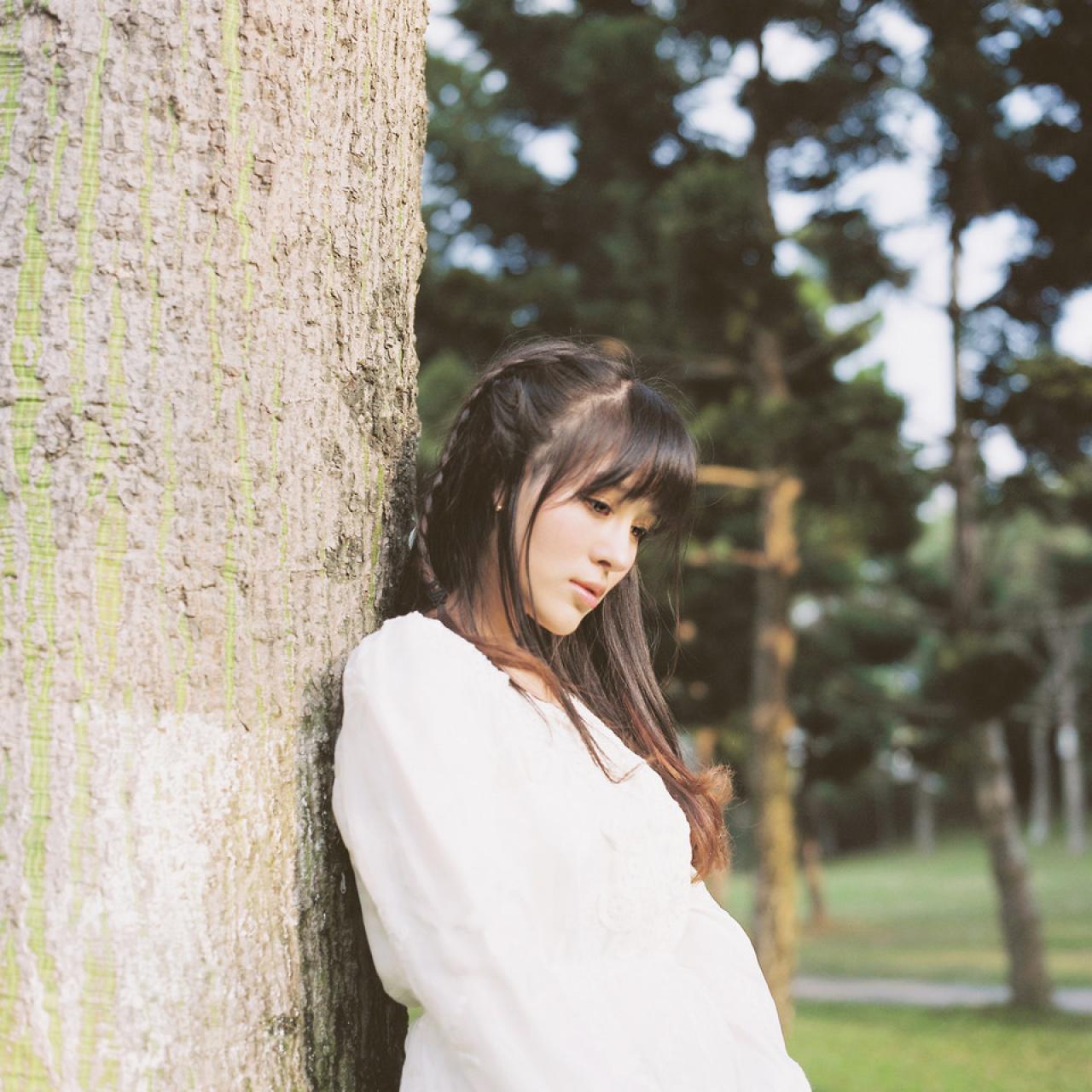 萌少女靠在树干低头深思