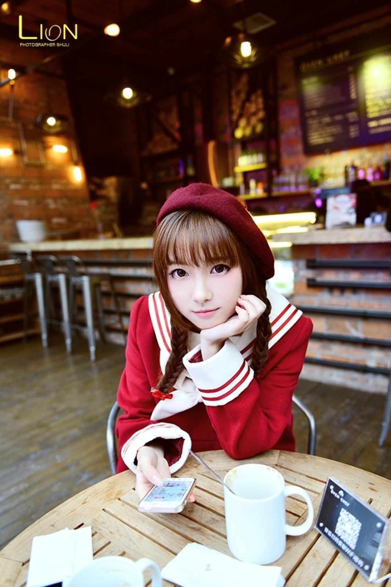 萌妹子左手撑着下巴，右手拿着手机，扒在餐桌上