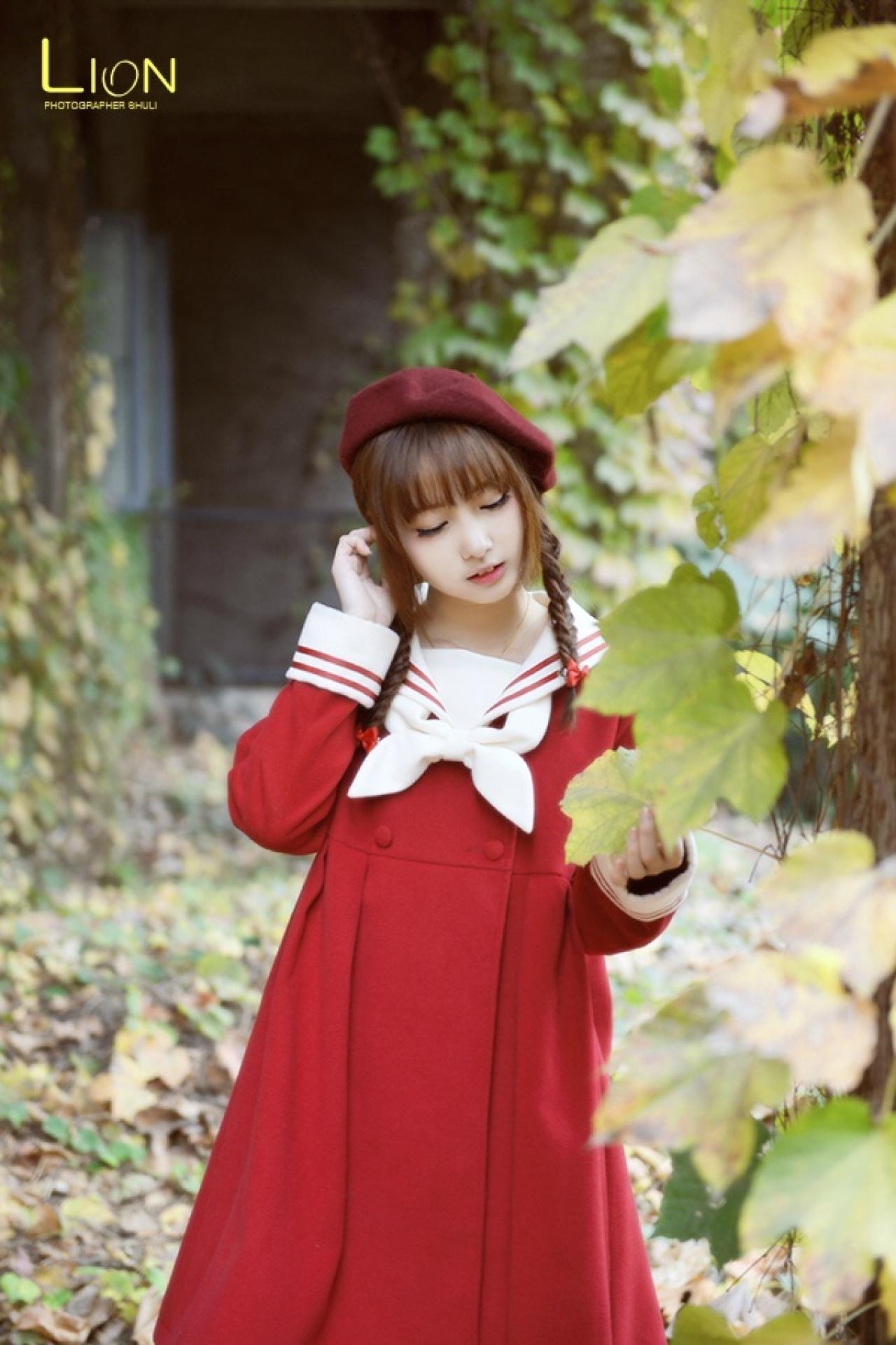 萌妹子左手捏着青黄的叶子，右手轻抚头发