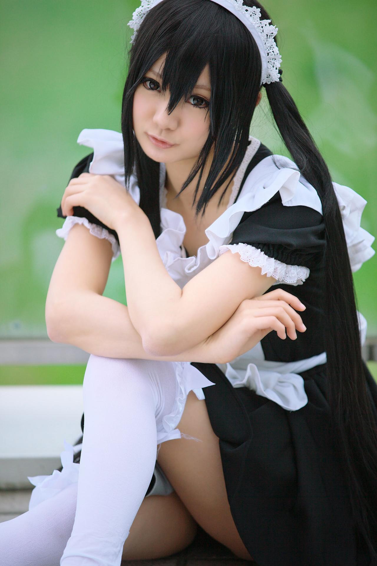 Maika扮演中野梓坐在地板上，双臂叠放在膝盖上