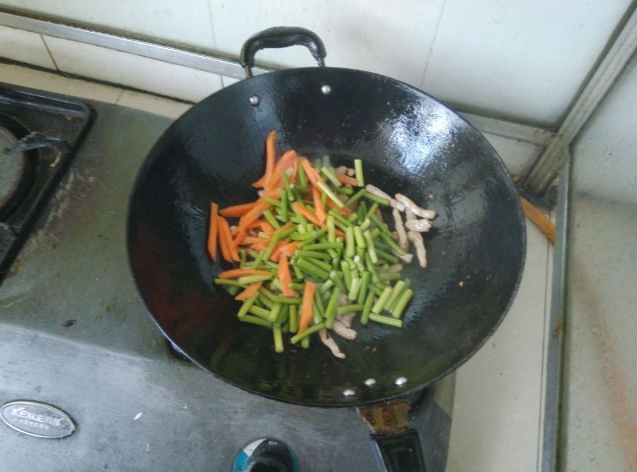 第六步，等待肉丝发白时，倒入蒜苔、胡萝卜，翻炒