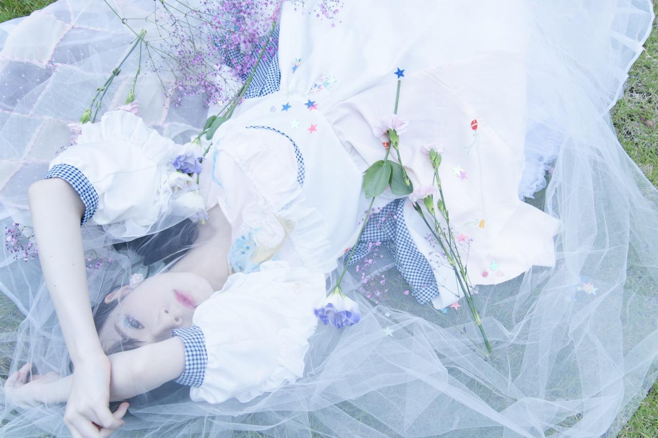 近衛りこ躺在草地，身上铺着玫瑰花束，点缀着星星