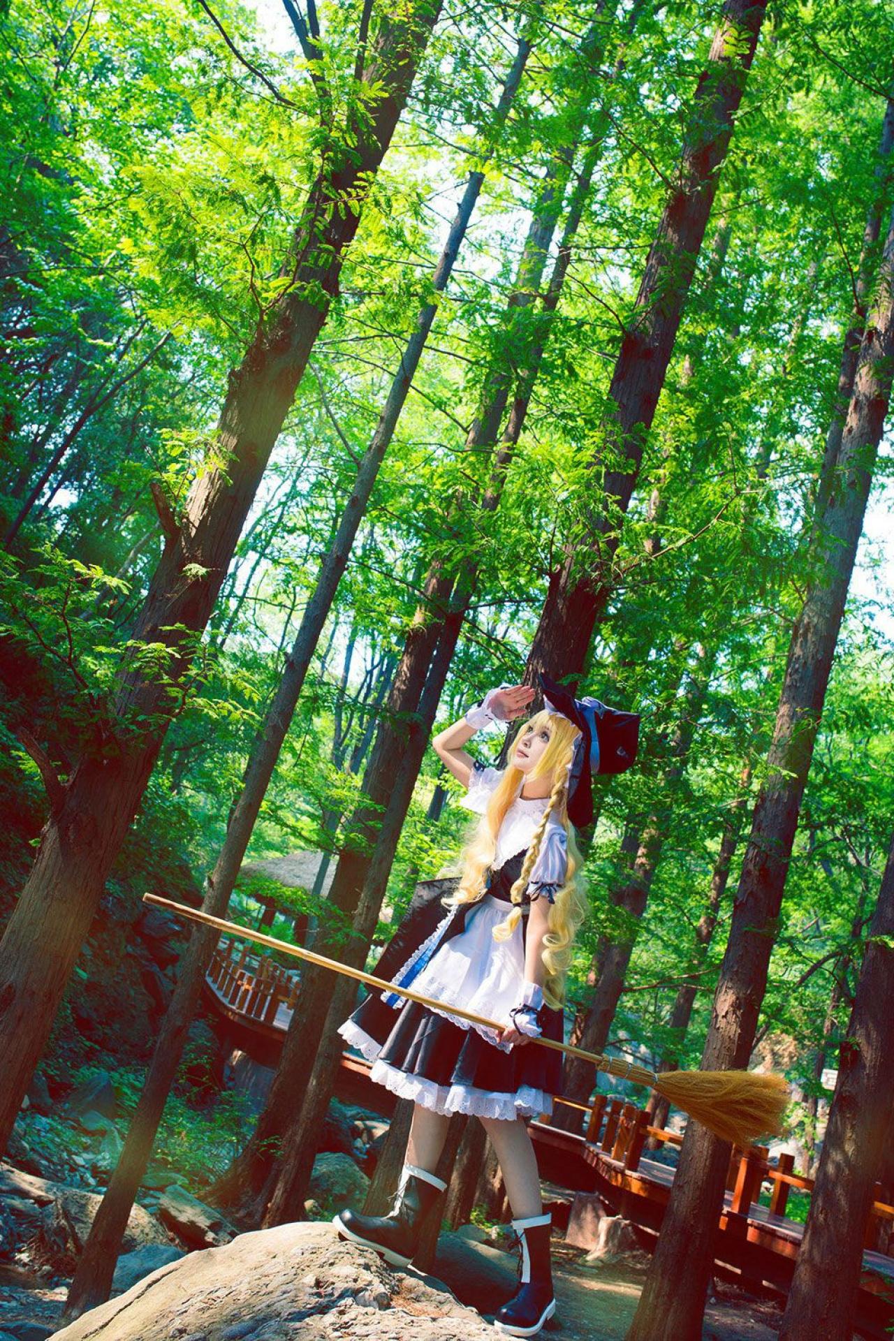 雨扮演雾雨魔理沙，左手遮挡阳光，右手提着扫把站在水边