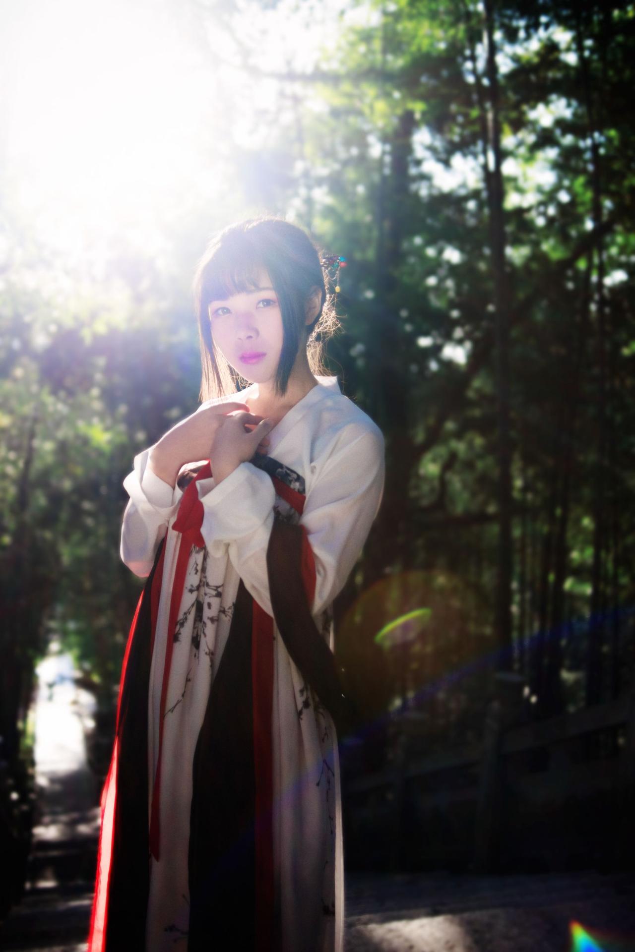 霓君在阳光下双手靠着放在胸前在林间驻足