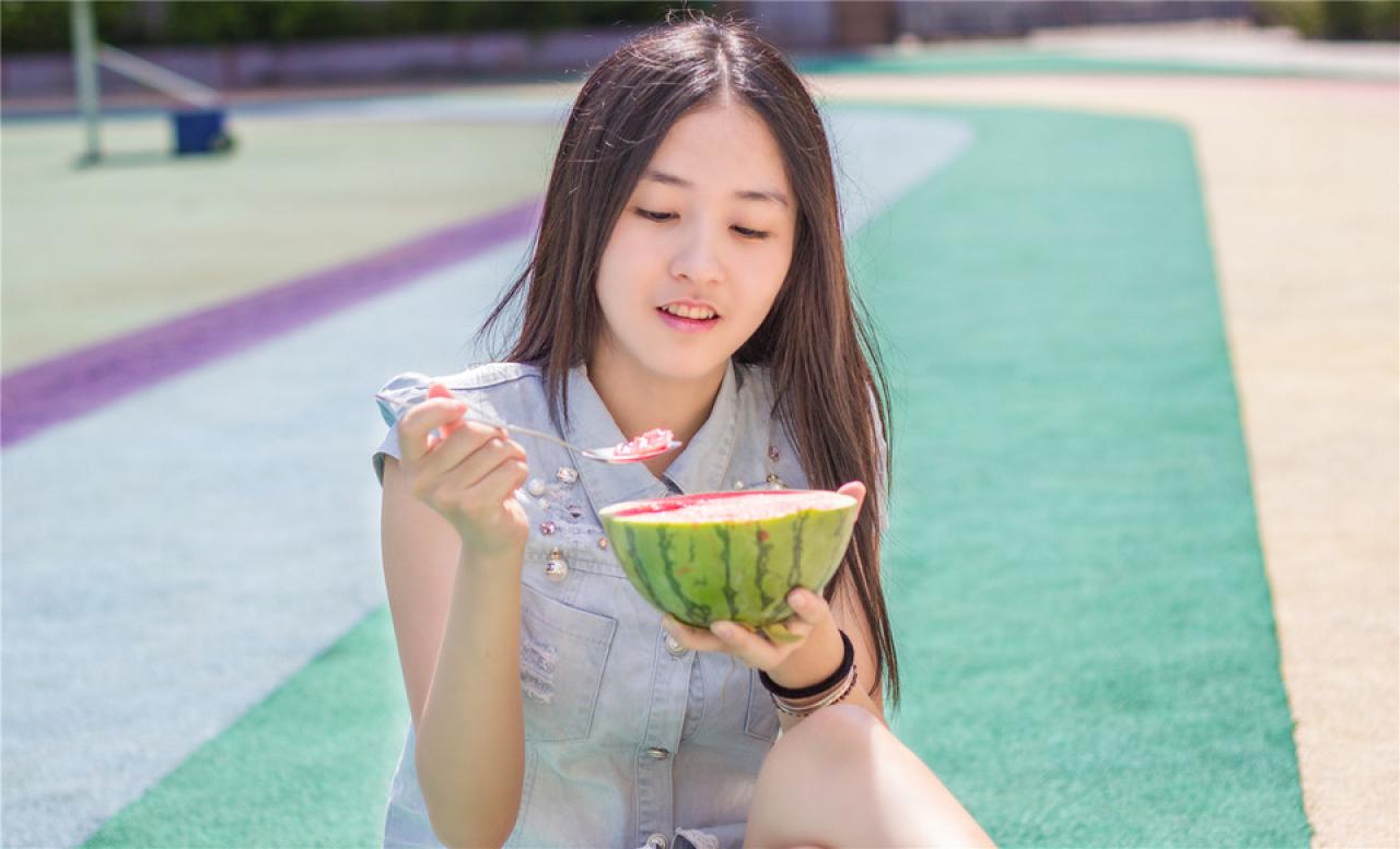 陈婕左手端着西瓜，右手拿着勺子，正挖起瓜瓤