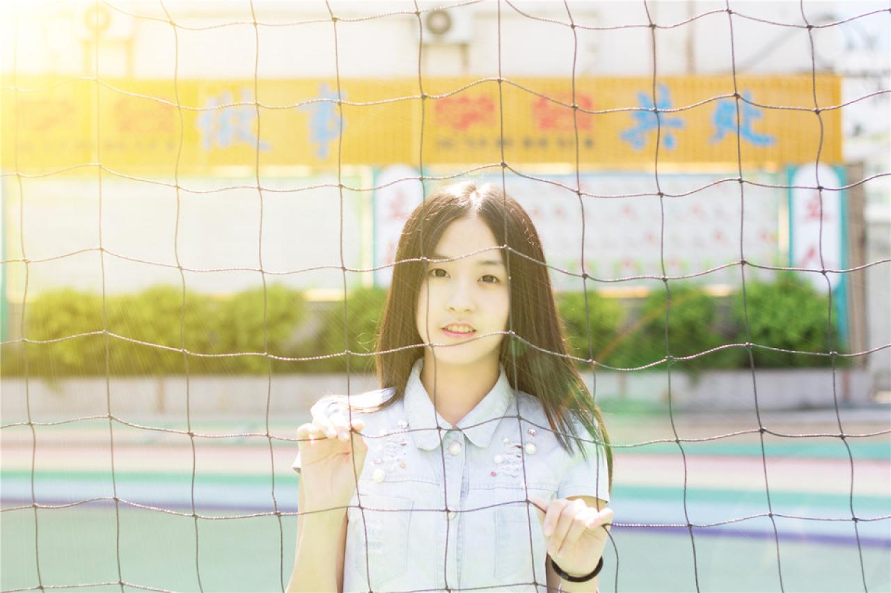 陈婕双手扒在球网后，上半身，正面照