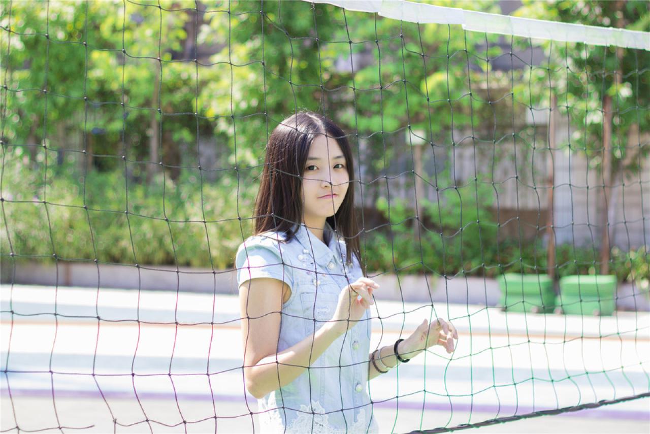 陈婕扒在球网后，撅嘴神情，上半身，侧面照