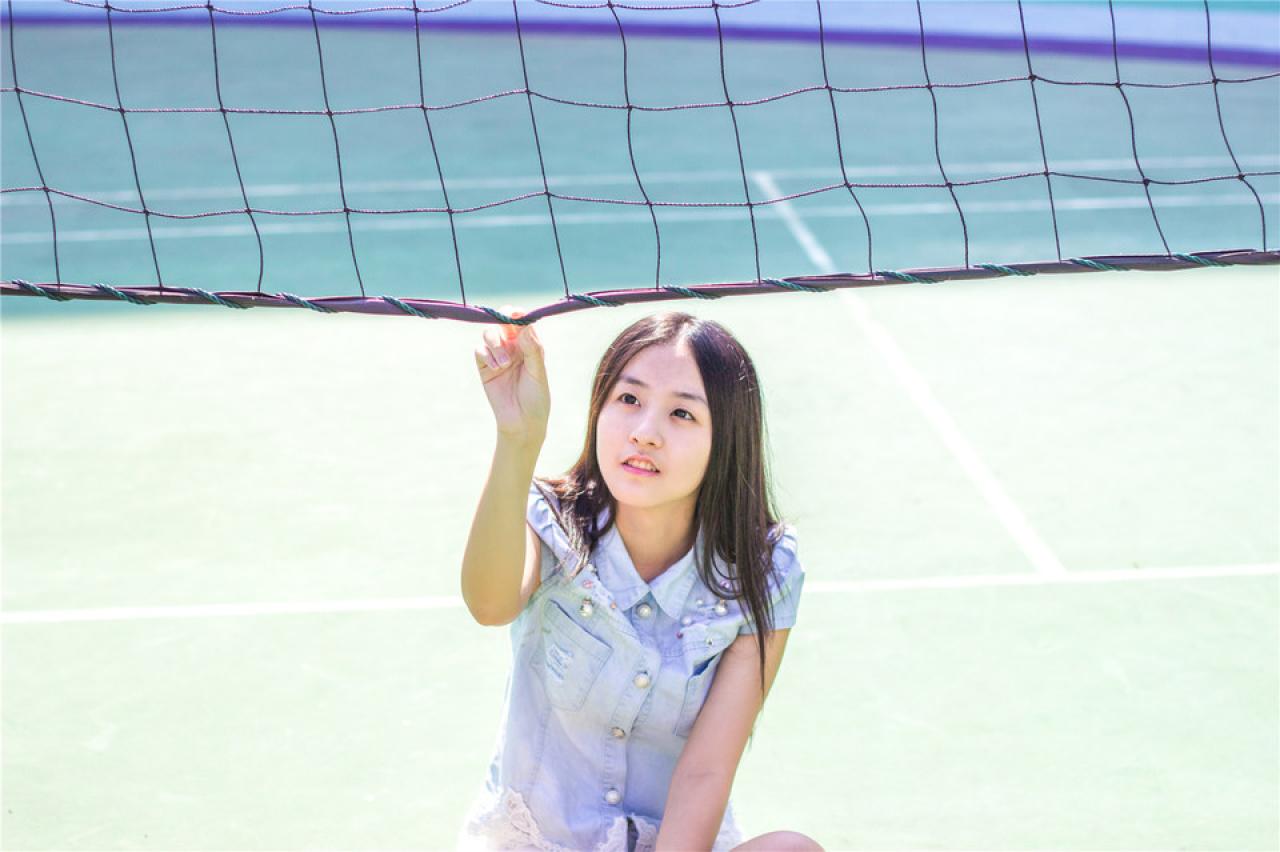 陈婕坐在球网下，右手捏着球网底边