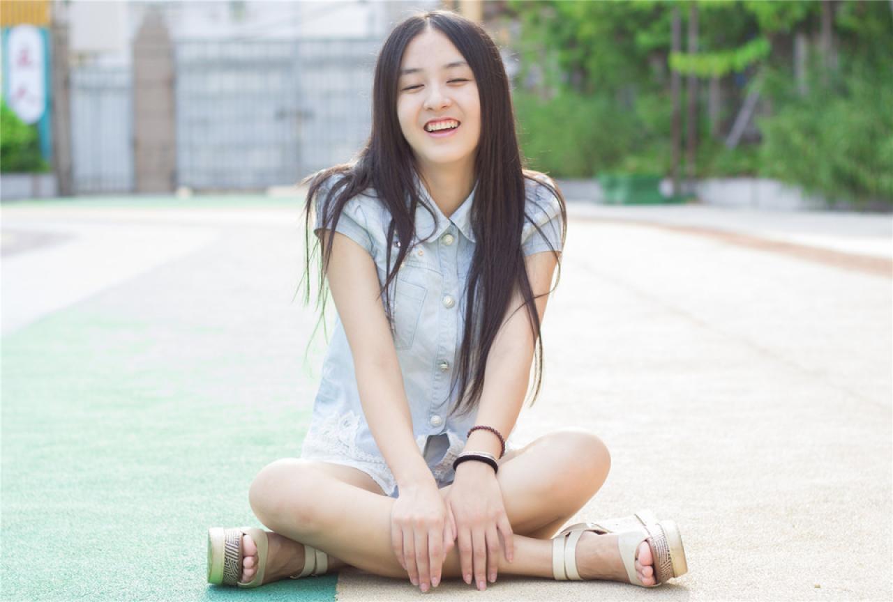 陈婕盘腿坐在跑道上，开心大笑的神情