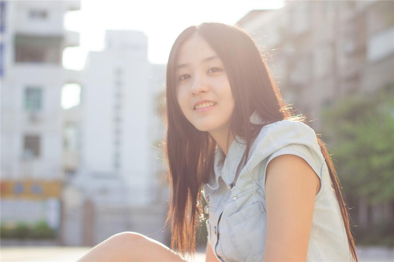 陈婕侧身坐在跑道上，阳光倾洒到脸部