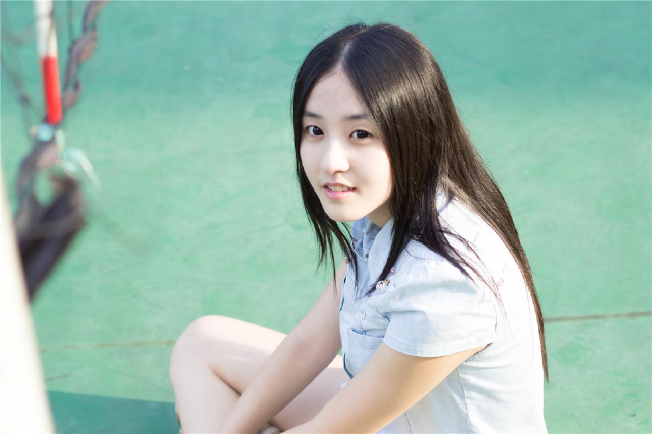 陈婕盘腿坐在球场上，侧目抬头看镜头