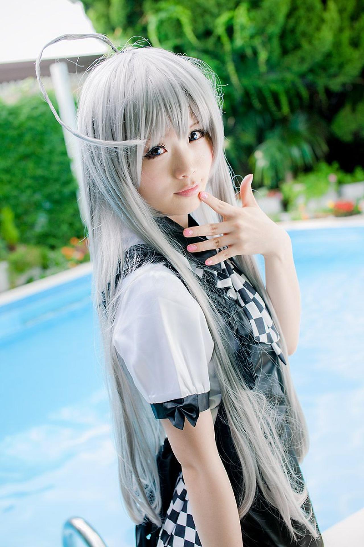 倉坂くるる站在游泳池旁，左手五指张开贴在嘴角