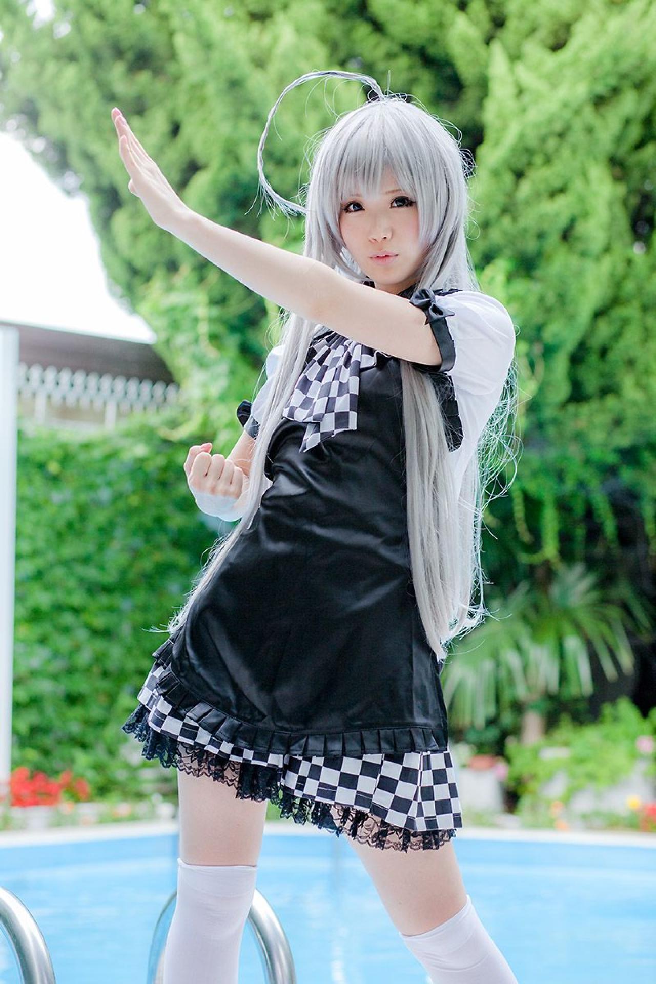 倉坂くるる站在游泳池旁，右手半握拳放在腰间，左臂伸出，嘟嘴卖萌